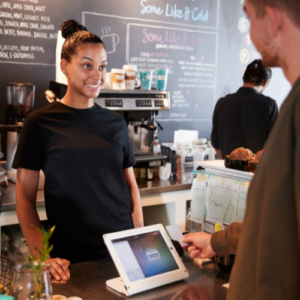 Happy sales women checking out a customer at a local coffee shop.