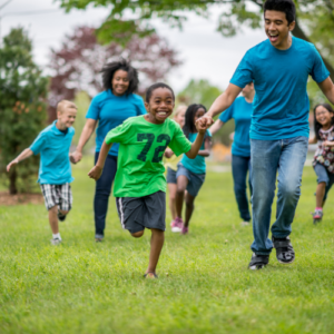 diverse group of adults and children running in the park